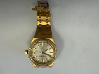 Audemars Piguet Royal Oak Auto 37 Ladies, б/у. Наручные часы «Audemars Piguet Royal Оаk Auto 37 Ladies ref. 15451or.zz.1256or.01» корпус ромбовидный, из металла золотистого цвета со вставкой из прозрачных камней по кругу, браслет из металла золотистого цвета с замком. На оборотной стороне…
