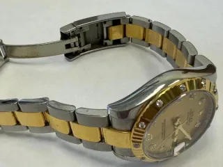 Rolex Datejust ref. 178313, б/у Наручные часы «Rolex Datejust ref. 178313» (на часах указан идентификационный номер «J9215513»), корпус круглый из металла серебристого цвета со вставкой из металла золотистого цвета и прозрачными камнями по кругу и на циферблате часов. Браслет из металла…