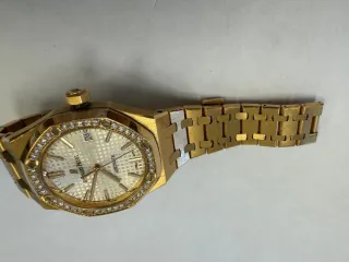 Audemars Piguet Royal Oak Auto 37 Ladies, б/у. Наручные часы «Audemars Piguet Royal Оаk Auto 37 Ladies ref. 15451or.zz.1256or.01» корпус ромбовидный, из металла золотистого цвета со вставкой из прозрачных камней по кругу, браслет из металла золотистого цвета с замком. На оборотной стороне…