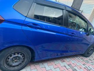 Honda Fit 2013 года выпуска, VIN кузова GK31020913 (GK3-1020913). Автомобиль после ДТП: глубокие вмятины и деформация левой передней двери (требуется замена), вмятины и царапины левой задней двери (требуется ремонт и покраска), вмятины порога с левой стороны. Царапины и сколы краски по всему…