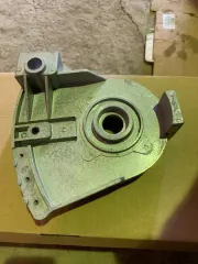 Запчасти для бензопилы и оборудование: гидроусилитель в сборе, трак гусеничный, электромотор, вал стальной соединительный. Металлическая крышка корпуса редуктора для цепной пилы серебристого цвета с техническими отверстиями и прорезями. Металлическое полотно для бензопилы продолговатой формы серого…