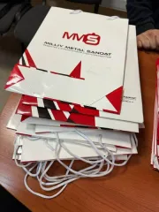 Канцелярские принадлежности и бумажная продукция MMS: картонные папки белого цвета с фирменным логотипом "MMS MILLIY METAL SANOAT" - 41шт, ручки черного цвета с фирменным логотипом "MMS MILLIY METAL SANOAT" - 49шт, блокнот с фирменным логотипом "MMS MILLIY METAL SANOAT" - 50шт, коврик черного цвета…