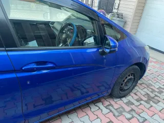 Honda Fit 2013 года выпуска, VIN кузова GK31020913 (GK3-1020913). Автомобиль после ДТП: глубокие вмятины и деформация левой передней двери (требуется замена), вмятины и царапины левой задней двери (требуется ремонт и покраска), вмятины порога с левой стороны. Царапины и сколы краски по всему…