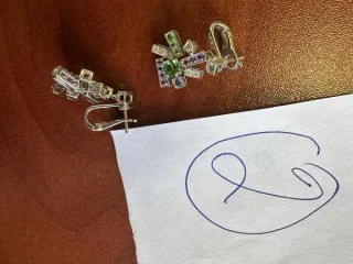 Серьги CHAUMET 750 из белого металла, выполненные в виде сложных геометрических фигур, на поверхности которых смеются вставки из камней. На застежках серег имеются штампованные надписи «CHAUMET», «750», «1042796».