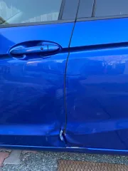 Honda Fit 2013 года выпуска, VIN кузова GK31020913 (GK3-1020913). Автомобиль после ДТП: глубокие вмятины и деформация левой передней двери (требуется замена), вмятины и царапины левой задней двери (требуется ремонт и покраска), вмятины порога с левой стороны. Царапины и сколы краски по всему…