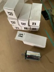 Запчасти для бензопилы и оборудование: гидроусилитель в сборе, трак гусеничный, электромотор, вал стальной соединительный. Металлическая крышка корпуса редуктора для цепной пилы серебристого цвета с техническими отверстиями и прорезями. Металлическое полотно для бензопилы продолговатой формы серого…